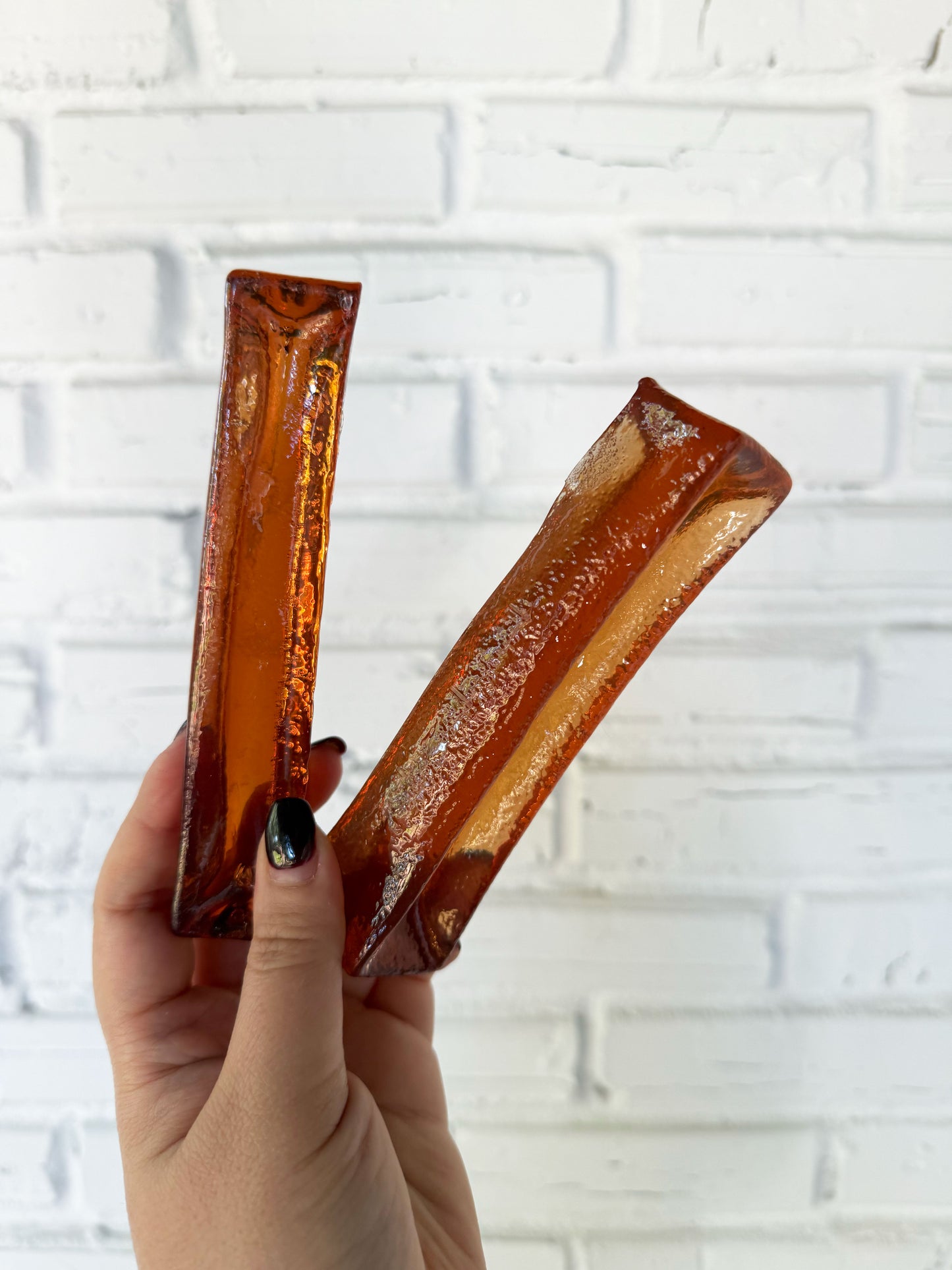 Hand holding two bacon collagen dental chews for dogs